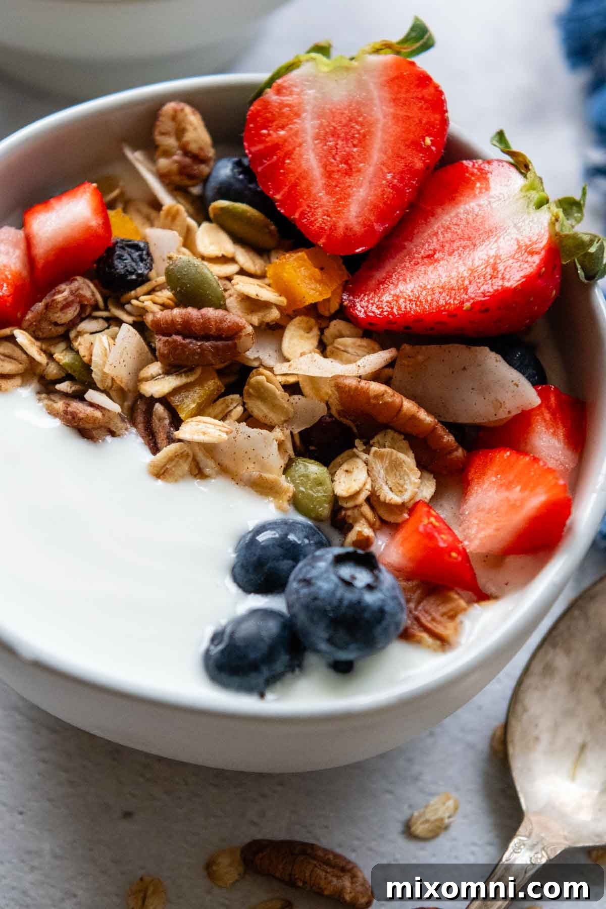 close up of a bowl of yogurt with muesli and fresh berries on top.