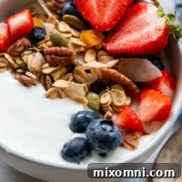 close up of a bowl of yogurt with muesli and fresh berries on top.