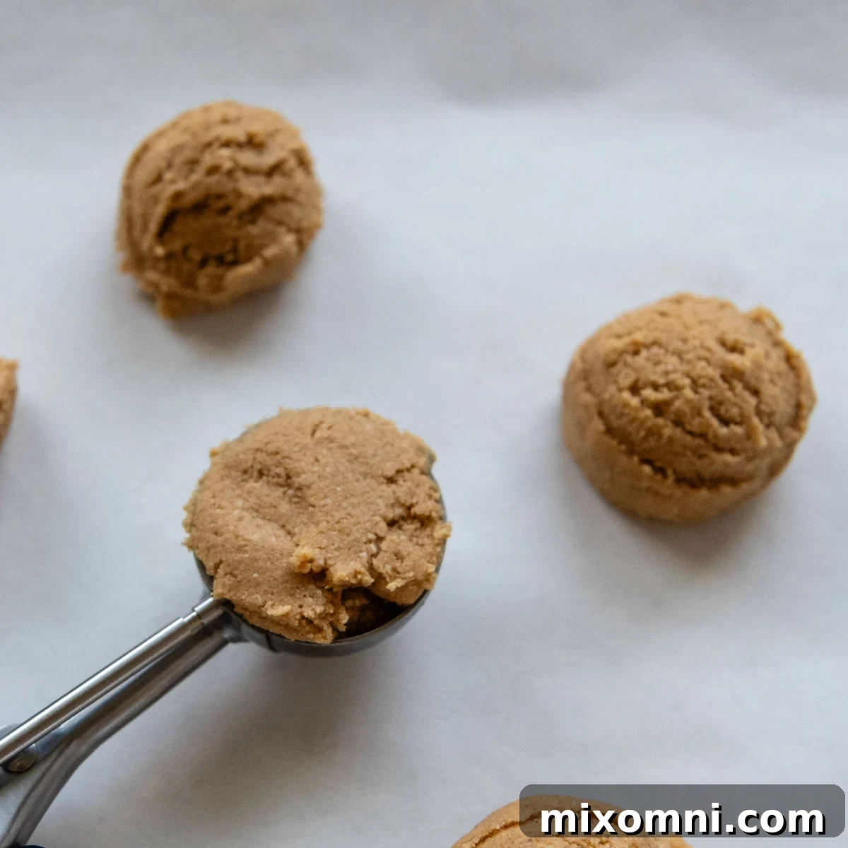 cookie scoop portioning out balls on a baking sheet.