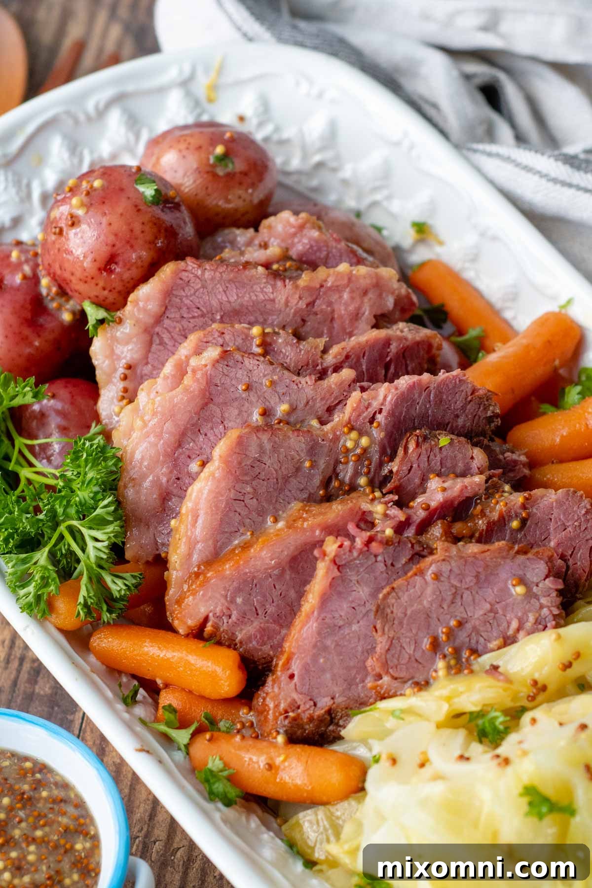 Sliced corned beef with tender cabbage, potatoes, and carrots arranged beautifully on a white platter, ready to serve.