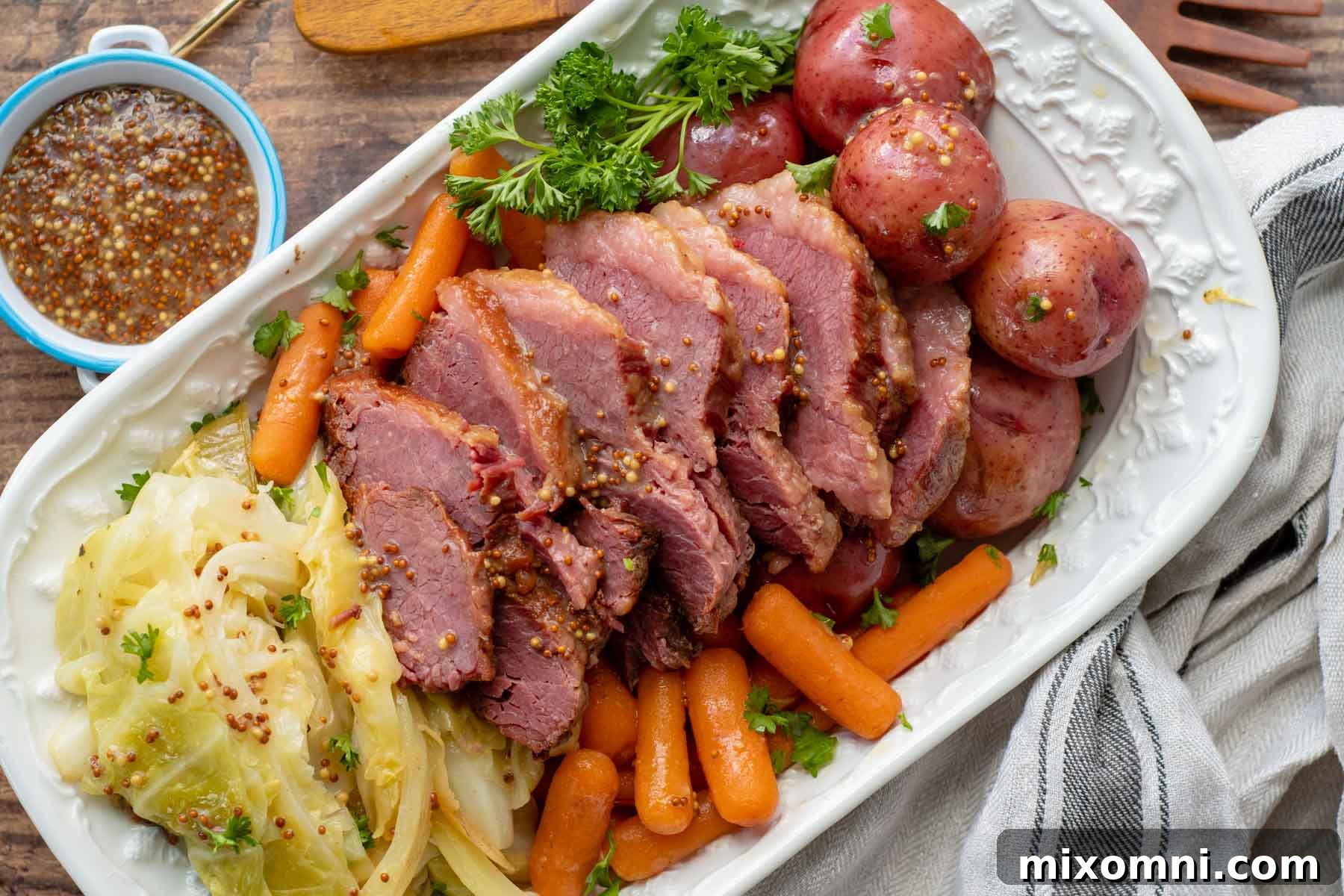 Overhead shot of a vibrant serving platter filled with tender sliced corned beef, perfectly cooked cabbage wedges, carrots, and potatoes, garnished with fresh parsley.