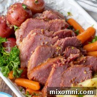 Sliced corned beef with cabbage, potatoes, and carrots on a white platter