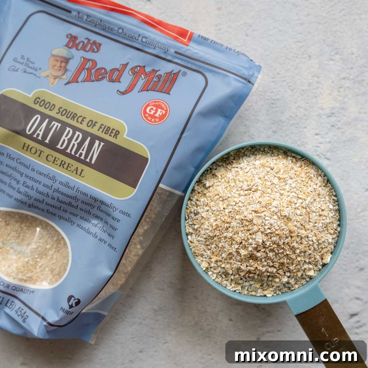 A measuring cup filled with gluten-free oat bran, placed next to its packaging.