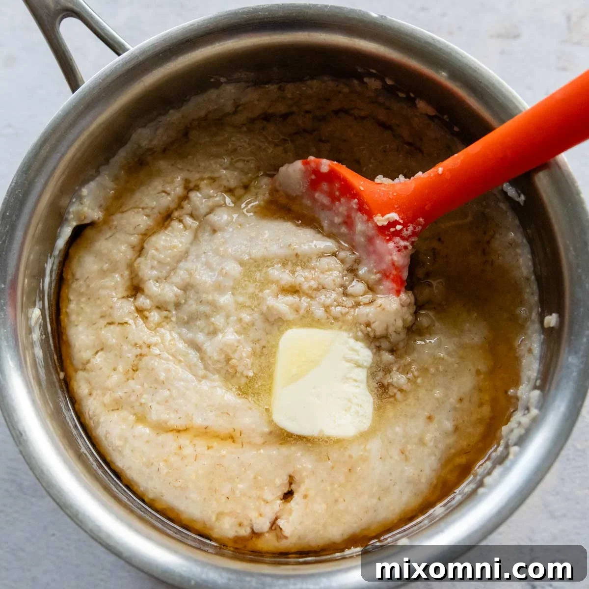 The oat bran porridge ingredients mixed together and gently cooking in a saucepan, showing its creamy texture.