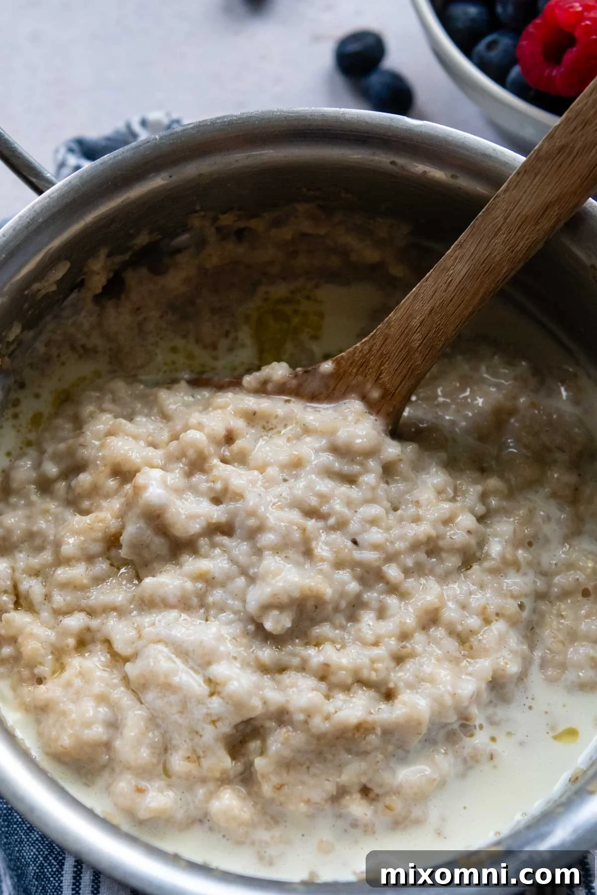 A close-up shot of creamy oat bran porridge cooking in a pot, demonstrating its smooth, thick texture before serving.