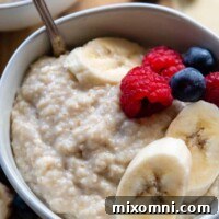 Close-up of oat bran porridge in a bowl topped with various fresh fruits and berries, highlighting its creamy texture.