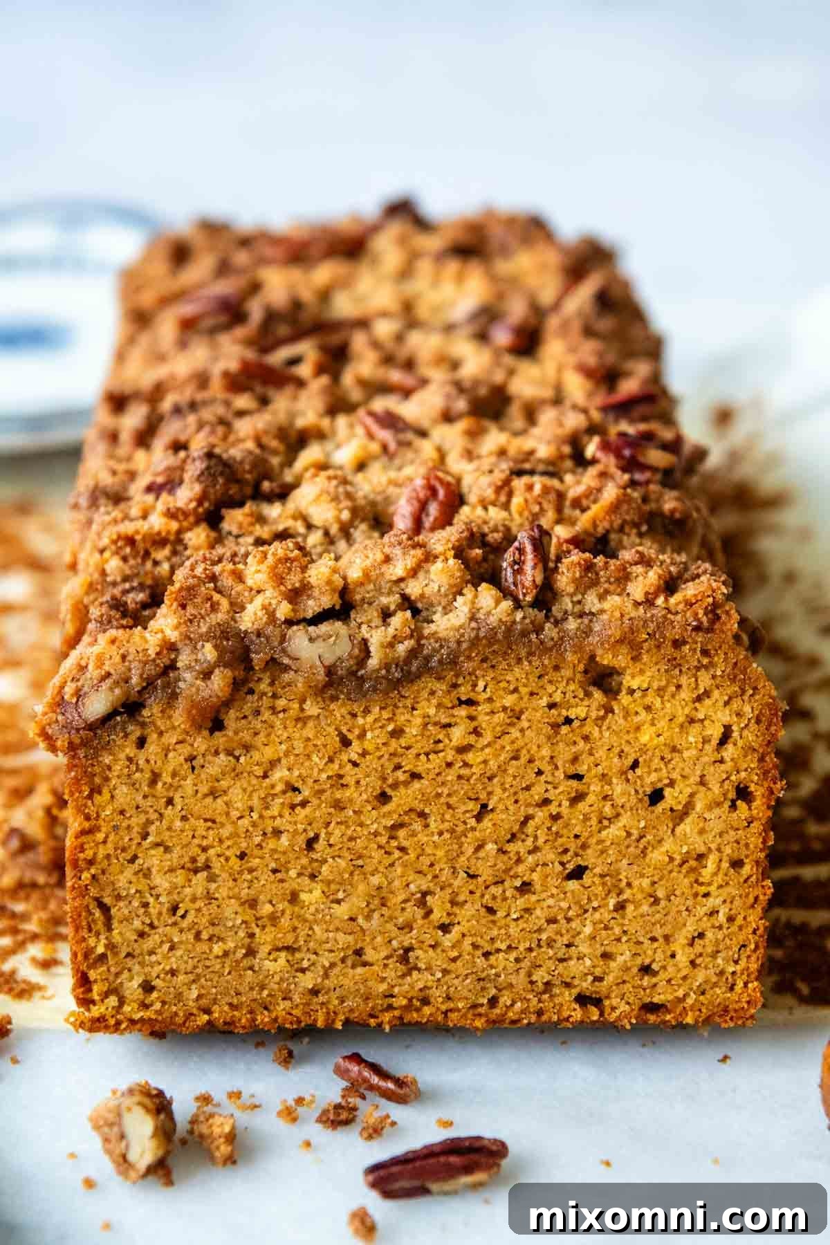 A slice of almond flour pumpkin bread showing the streusel topping and the fluffy interior.