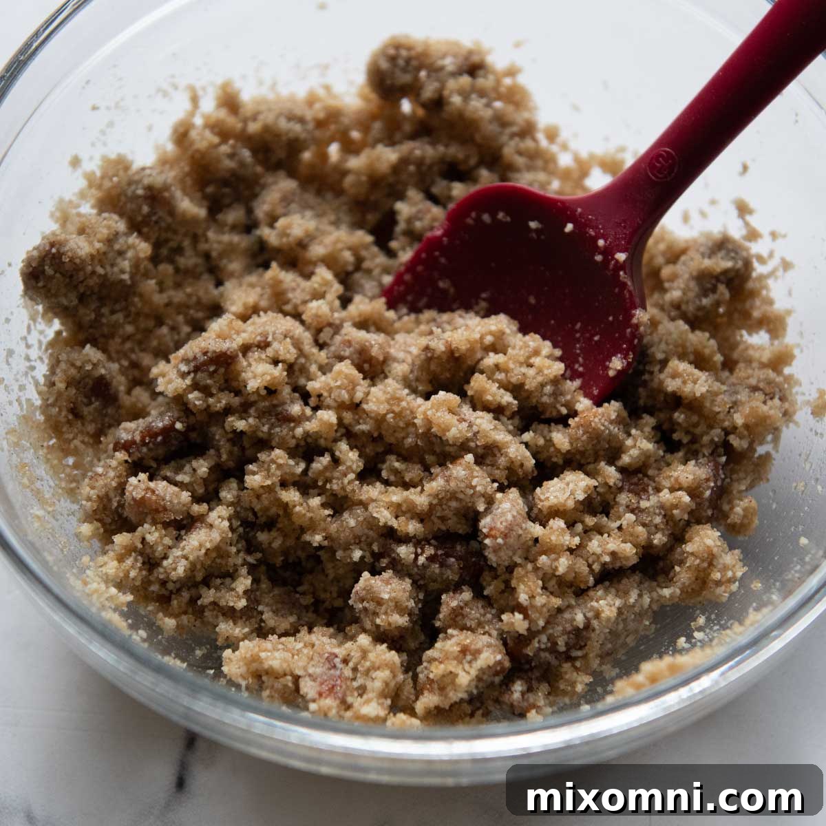 Streusel ingredients being mixed in a glass bowl.