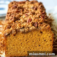 Almond flour pumpkin bread showing streusel on top with a slice removed, revealing the fluffy interior.
