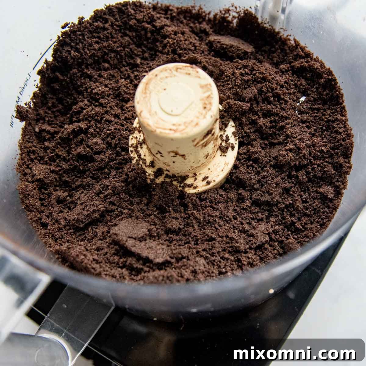 Gluten-free Oreos are crushed into fine crumbs in a food processor, ready for the melted butter.