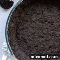 A baked gluten-free Oreo crust in a glass pie dish, showcasing its perfect texture and readiness for filling.