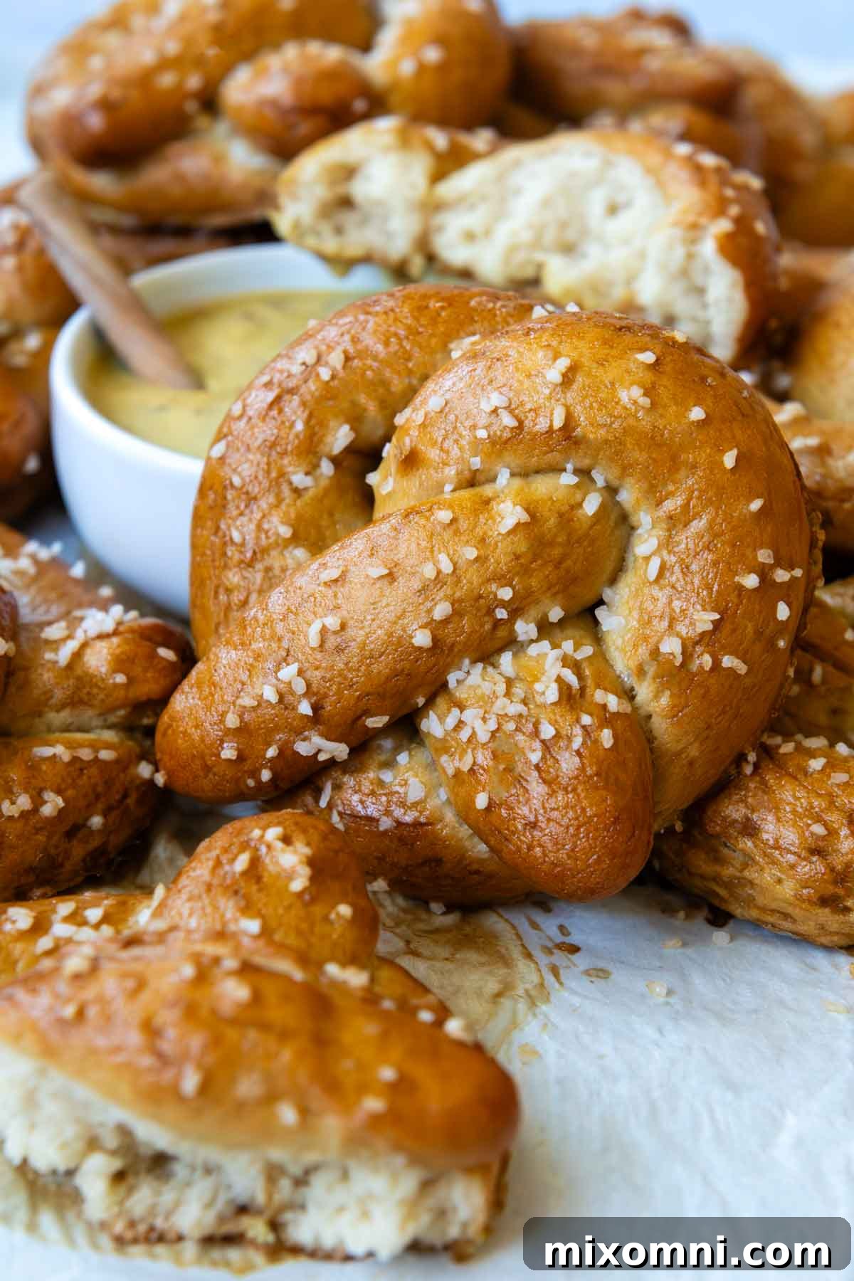 a pretzel leaning up against bowl of mustard dipping sauce.