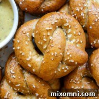 close up overhead view of a gluten-free pretzel that shows the golden brown color of the pretzel and the white salt flakes with a bowl of mustard dipping sauce off to the left side