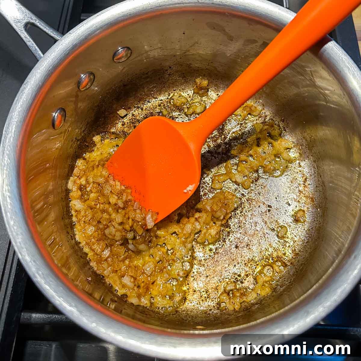 Diced onions cooking in melted butter in a saucepan, beginning to soften and turn translucent.