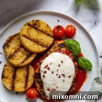 Overhead shot of grilled chicken parmesan with grilled polenta next to it on a white plate