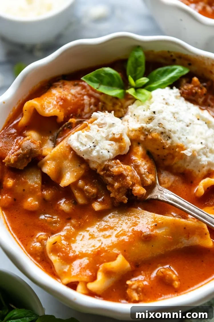 Gluten-Free Lasagna Soup displayed in a white bowl with a garnish of greenery and a spoon.