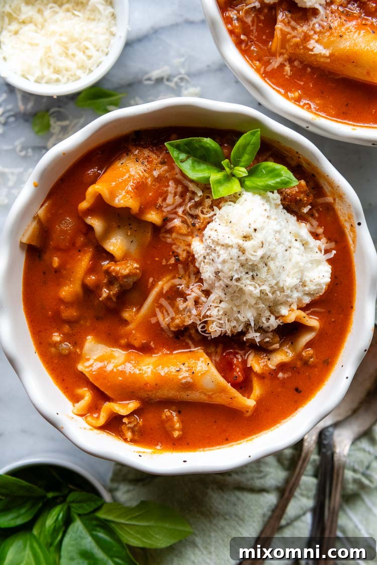 overhead shot of completed lasagna soup in a white bowl with basil garnish.