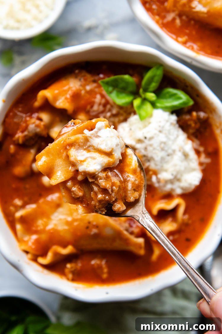 White bowl filled with soup topped with ricotta topping and garnished with fresh basil.