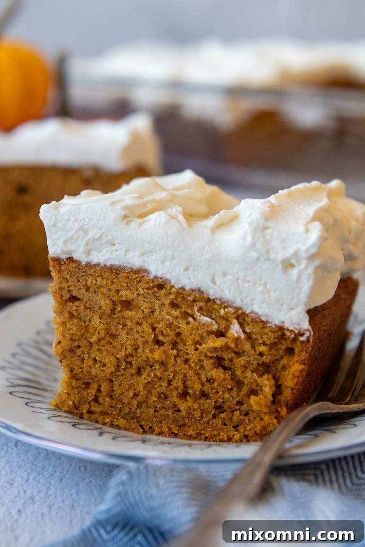 slice of cake with frosting sitting on a plate with a fork.