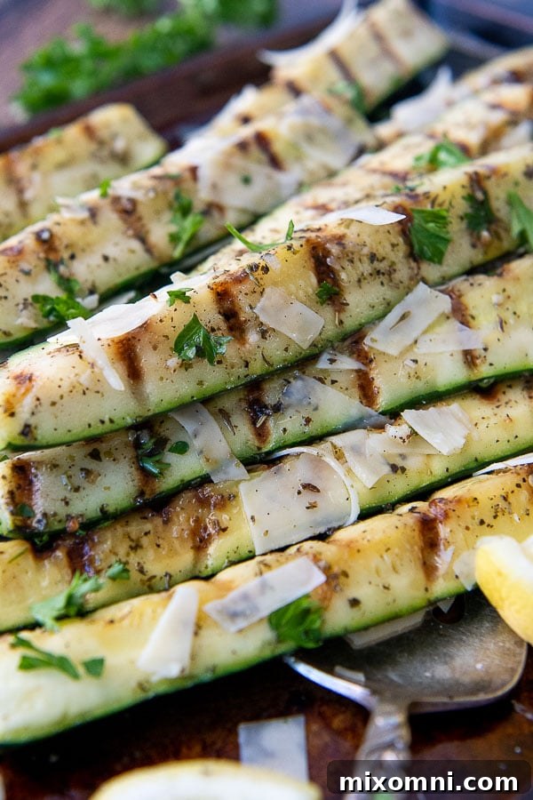 a grilled zucchini spear with lemon wedges around it.