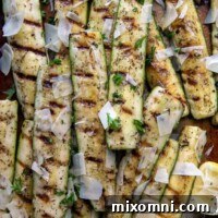 overhead shot of grilled zucchini and squash on a sheet pan with a serving utensil underneath