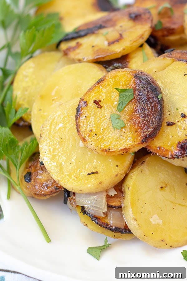 A close-up of golden grilled potatoes and caramelized onions on a white plate, garnished with fresh parsley.