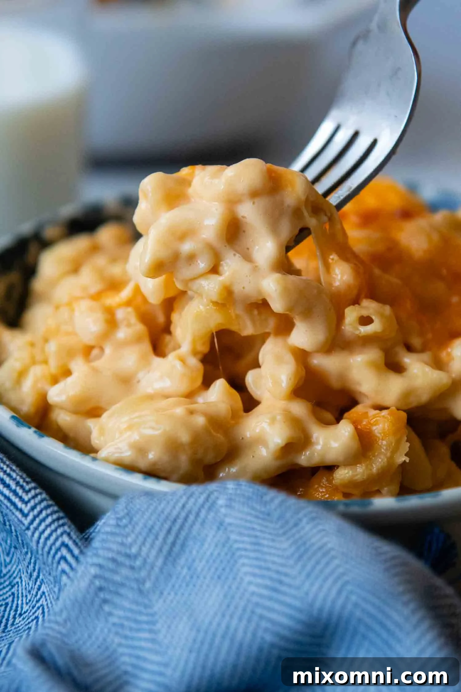Gluten-Free Mac and Cheese being lifted out of a bowl by a fork, showcasing its creamy texture.