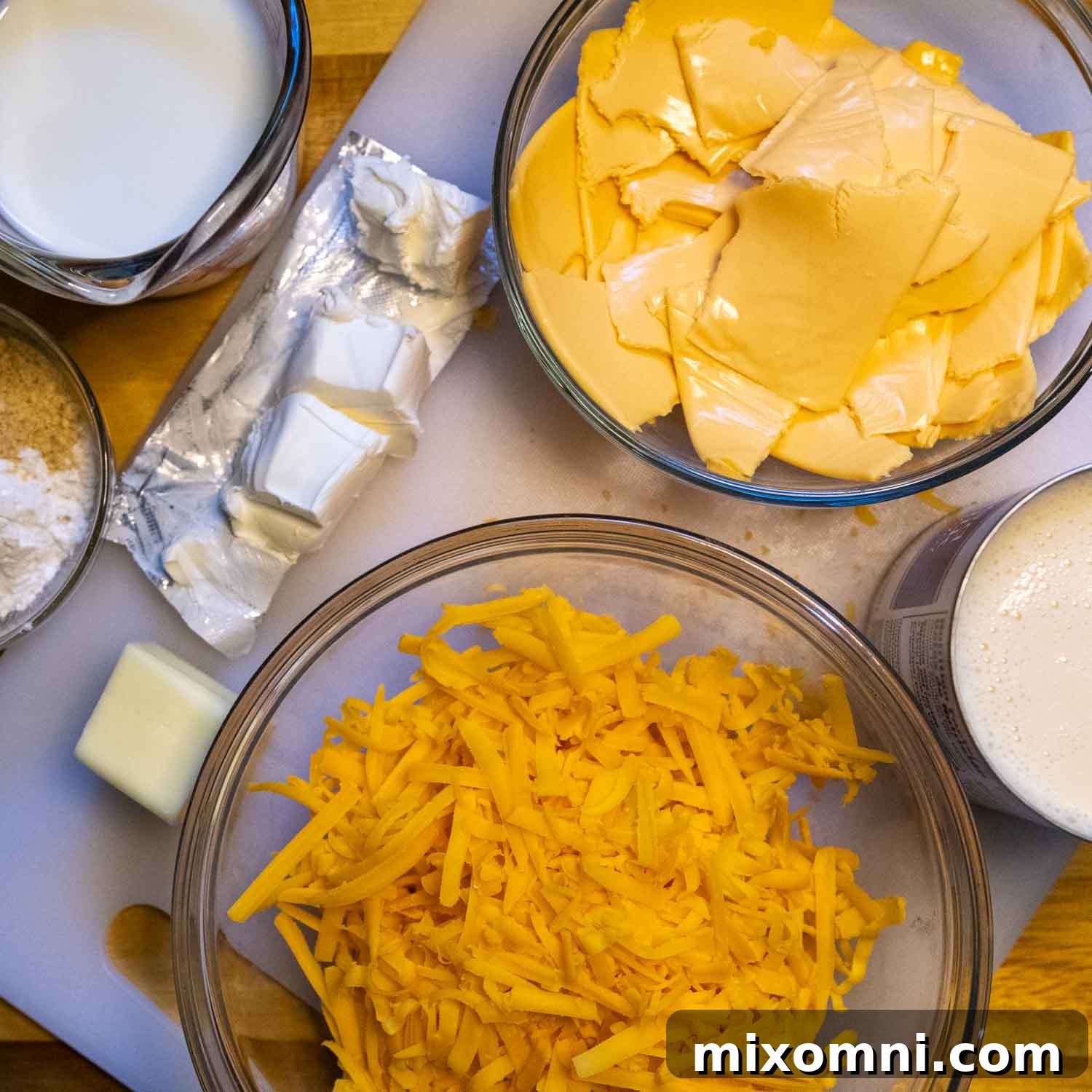 Ingredients on a white cutting board, neatly prepped for mac and cheese.