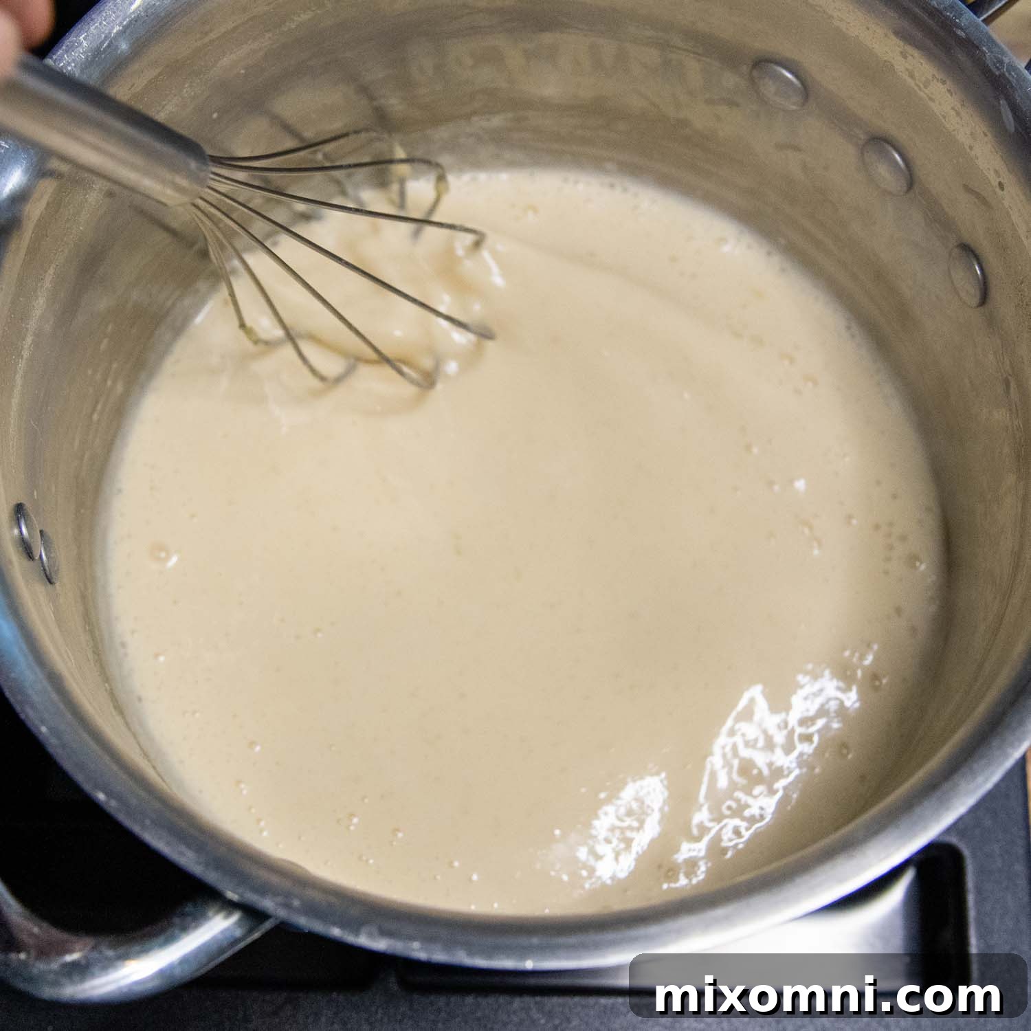 Whisking butter and flour together in a sauce pan to form a roux.