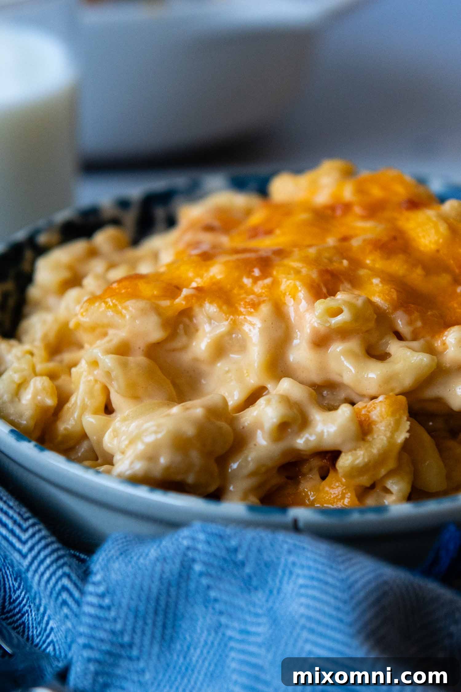 Cooked mac and cheese in a blue bowl sitting on a blue napkin, ready to be enjoyed.