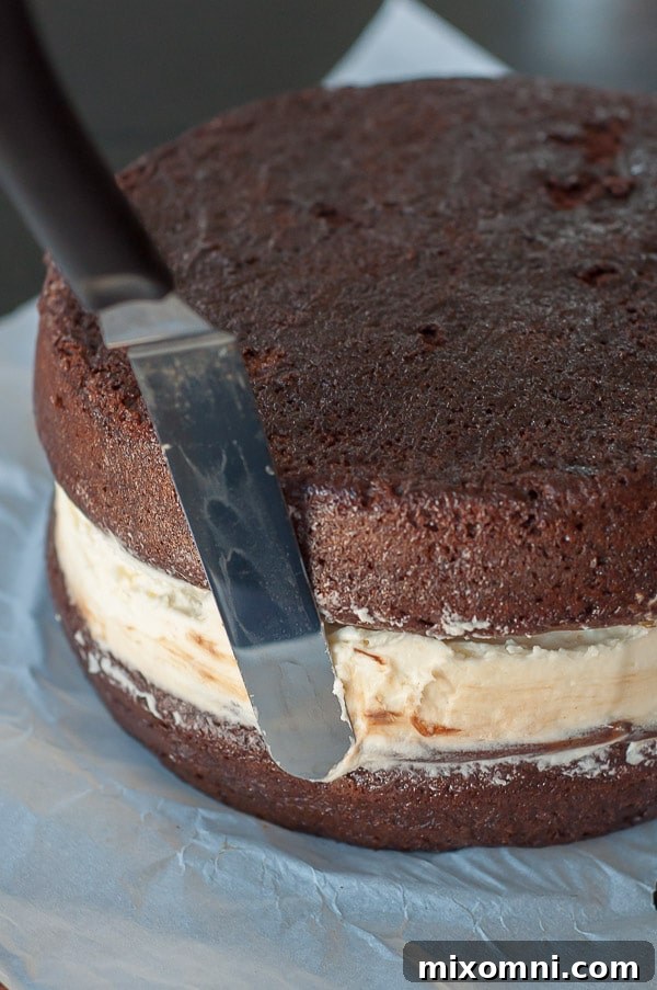 A close-up image demonstrating how to spread the cream filling evenly between chocolate cake layers for a Ding Dong cake.
