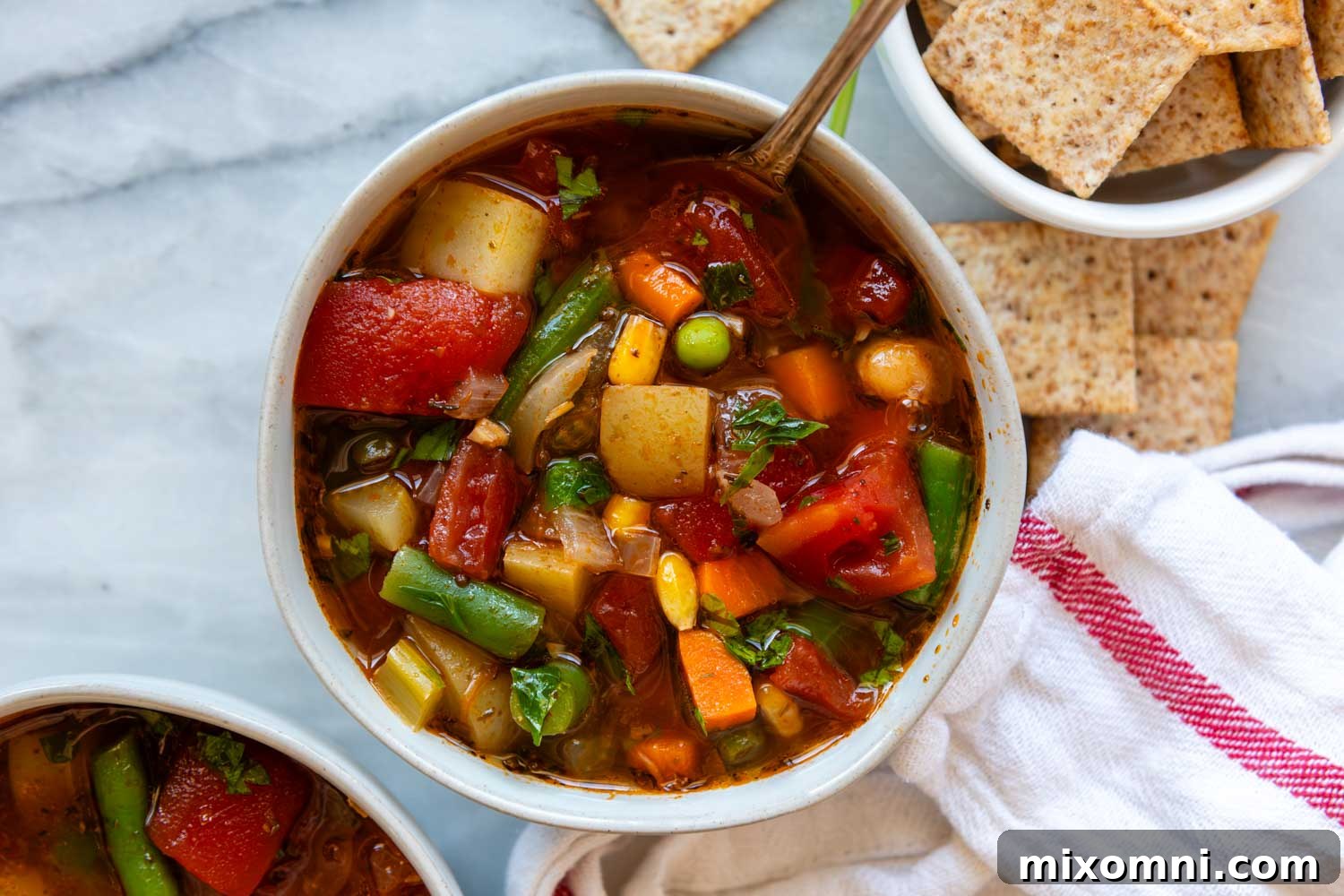 A bowl of gluten-free vegetable soup served with crackers, ready to eat.