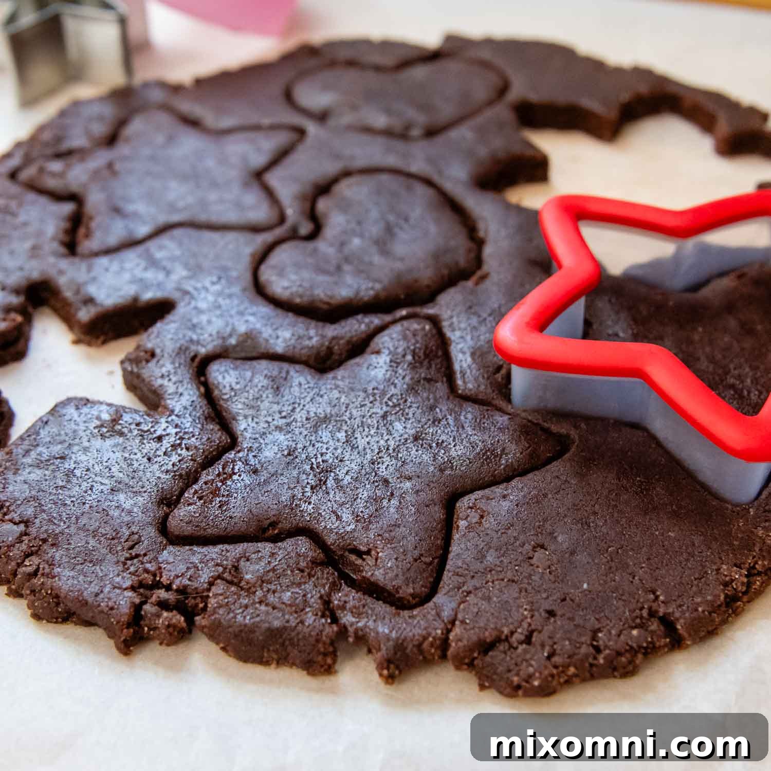 A red star-shaped cookie cutter pressing into the rolled-out Basler Brunsli cookie dough.