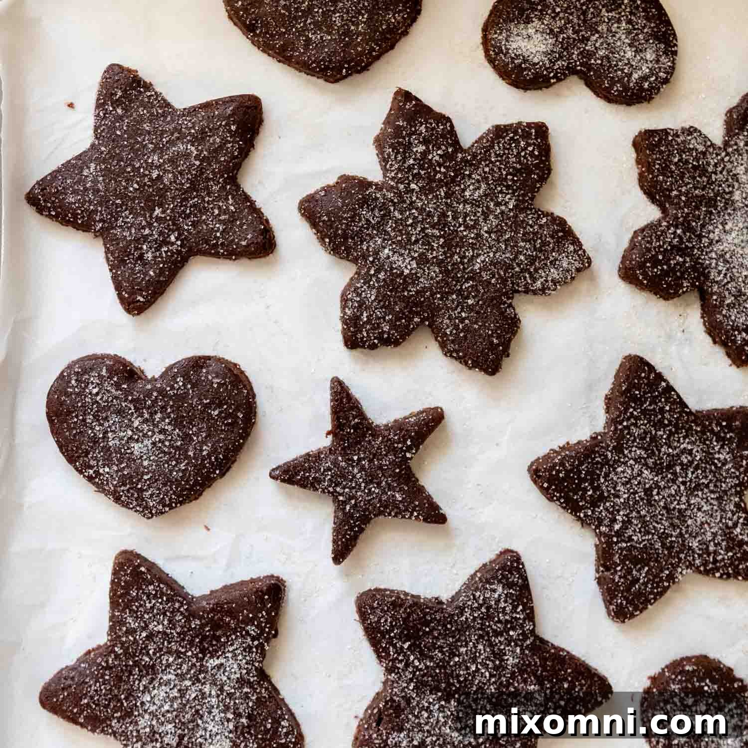 Several Basler Brunsli cookies, freshly cut into various shapes, resting on parchment paper before baking.