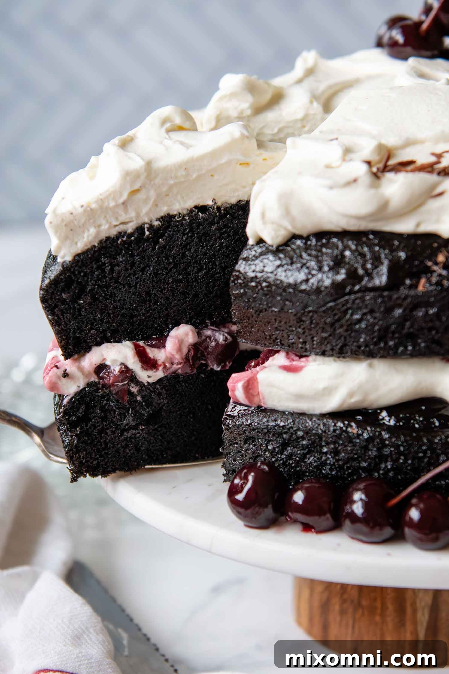 Close up of a stunning, impeccably decorated Gluten-Free Black Forest Cake, showcasing its layers of chocolate cake, whipped cream, and cherries.