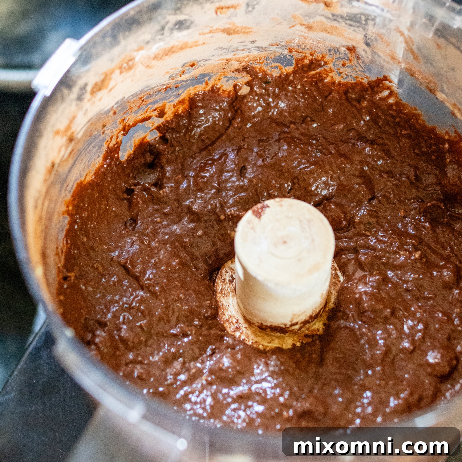 Rich chocolate brownie batter, mixed and ready for baking, within a food processor.