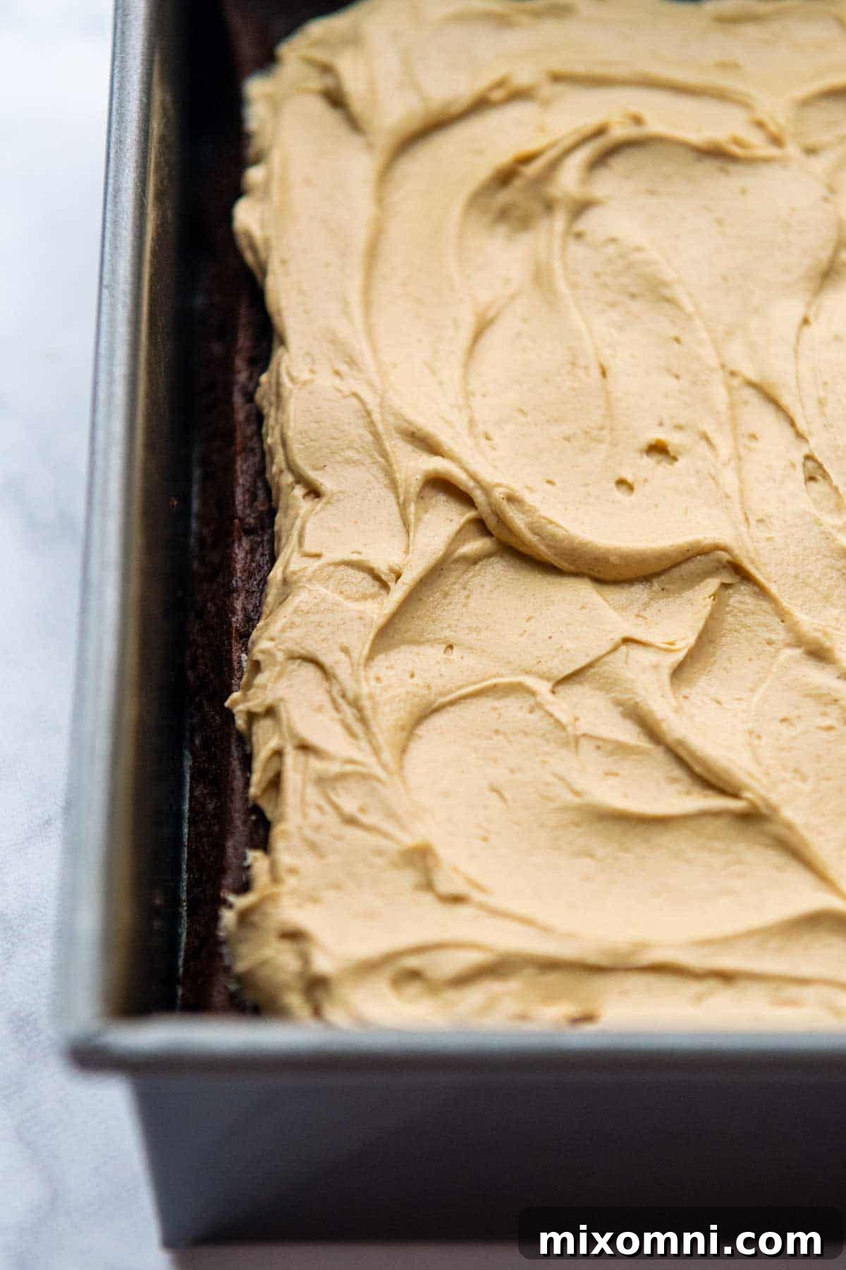 Close-up view of fluffy peanut butter frosting beautifully spread over the baked brownies.