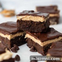 One zucchini brownie with peanut frosting on top of two other ones and chocolate chips around