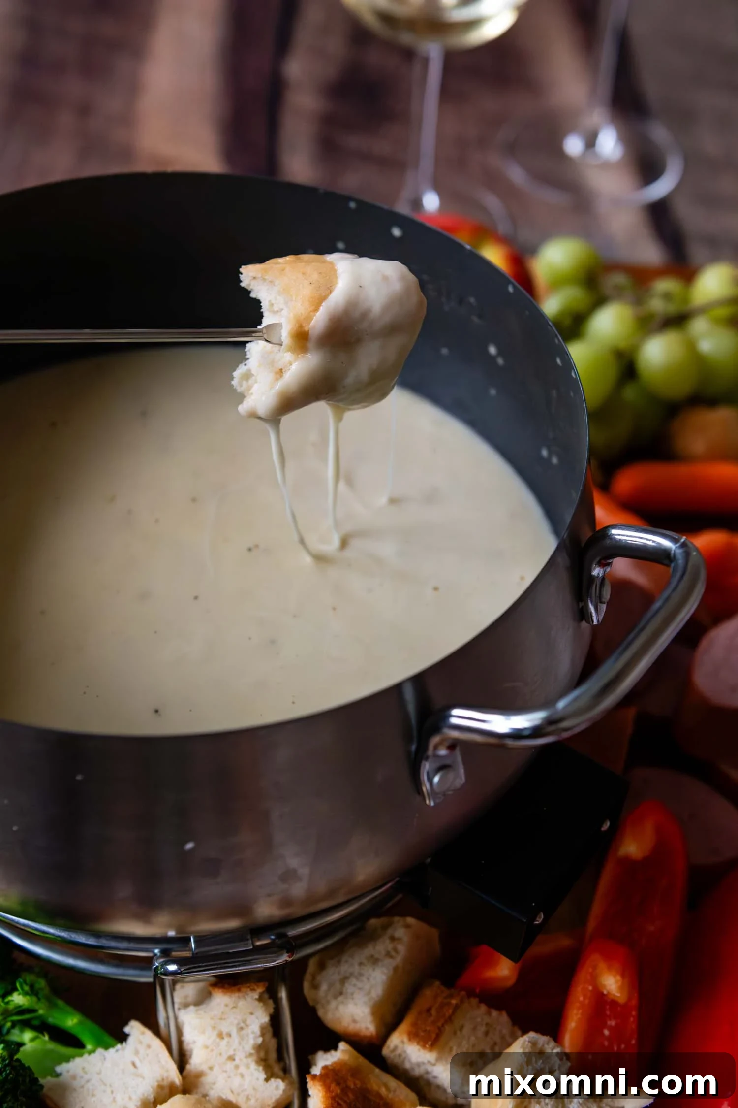 Piece of bread dripping with cheese having been dipped in Gluten-Free Cheese Fondue.