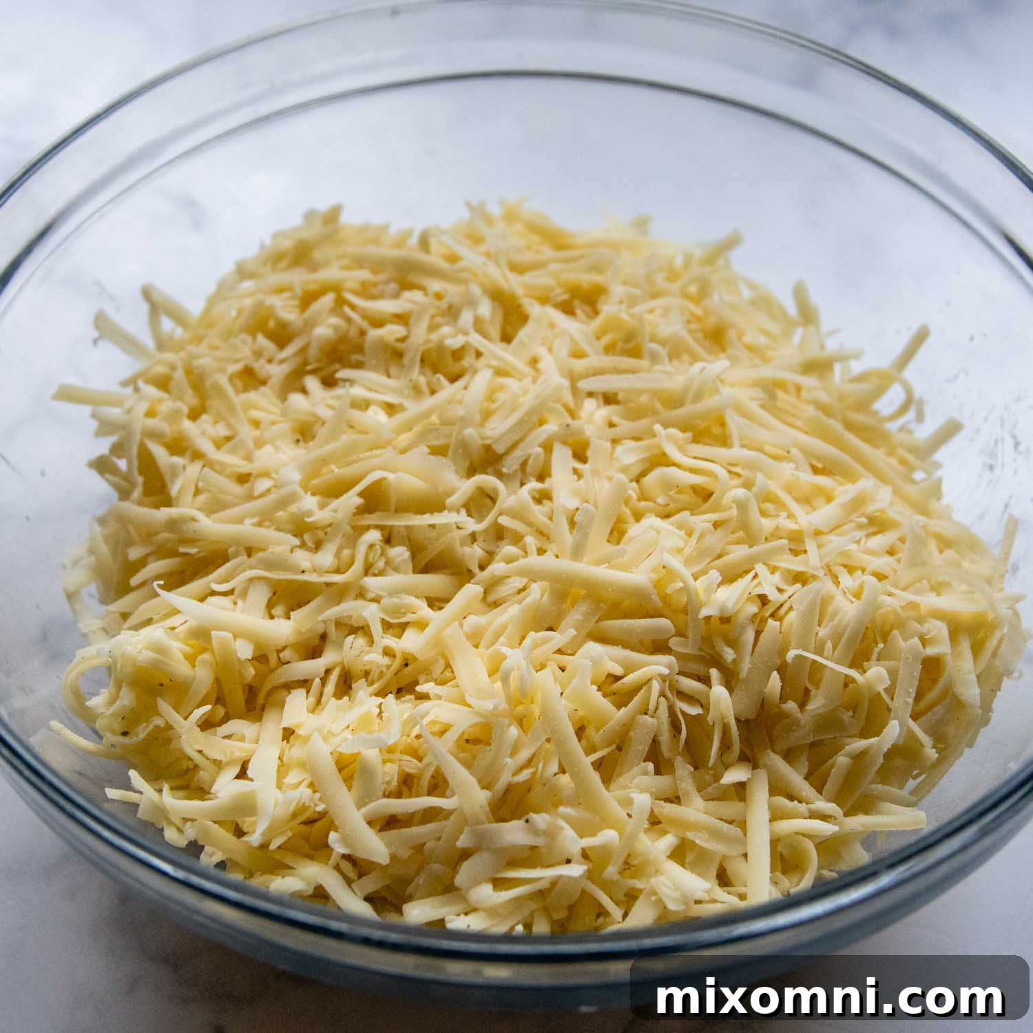 Glass bowl full of shredded cheese.