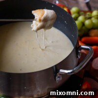 Piece of bread dripping with cheese having been dipped in Gluten-Free Cheese Fondue.