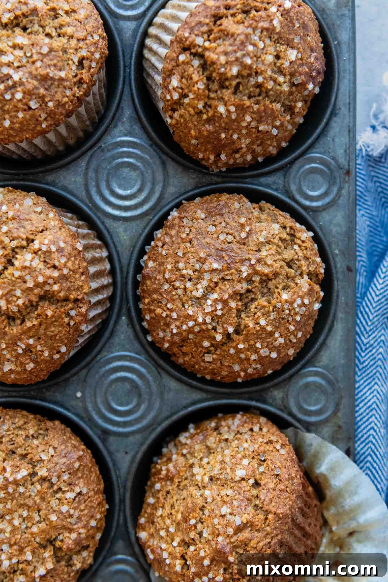A batch of freshly baked gluten-free oat bran muffins in a muffin tin, golden and perfectly risen.