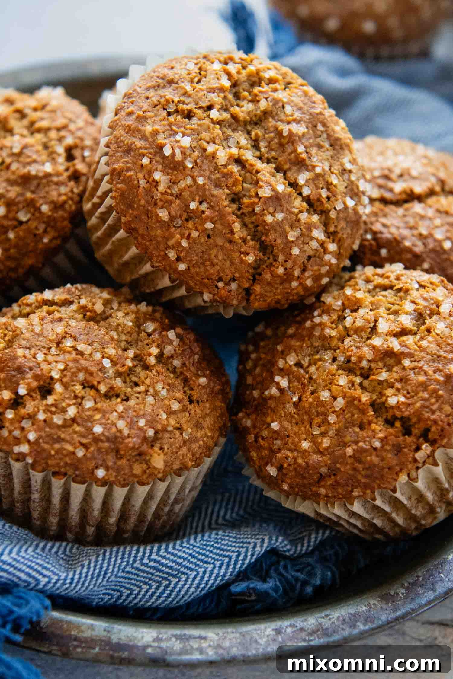 Two freshly baked gluten-free oat bran muffins stacked on a plate, showing their moist interior and perfect domed tops.