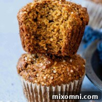 Two Gluten-Free Bran Muffins stacked with the top muffin having a bit taken out of it showing the inside texture.
