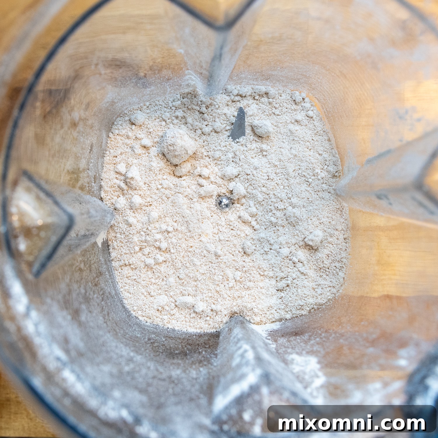 Close-up shot of dry rolled oats being blended into fine oat flour in a high-speed blender.