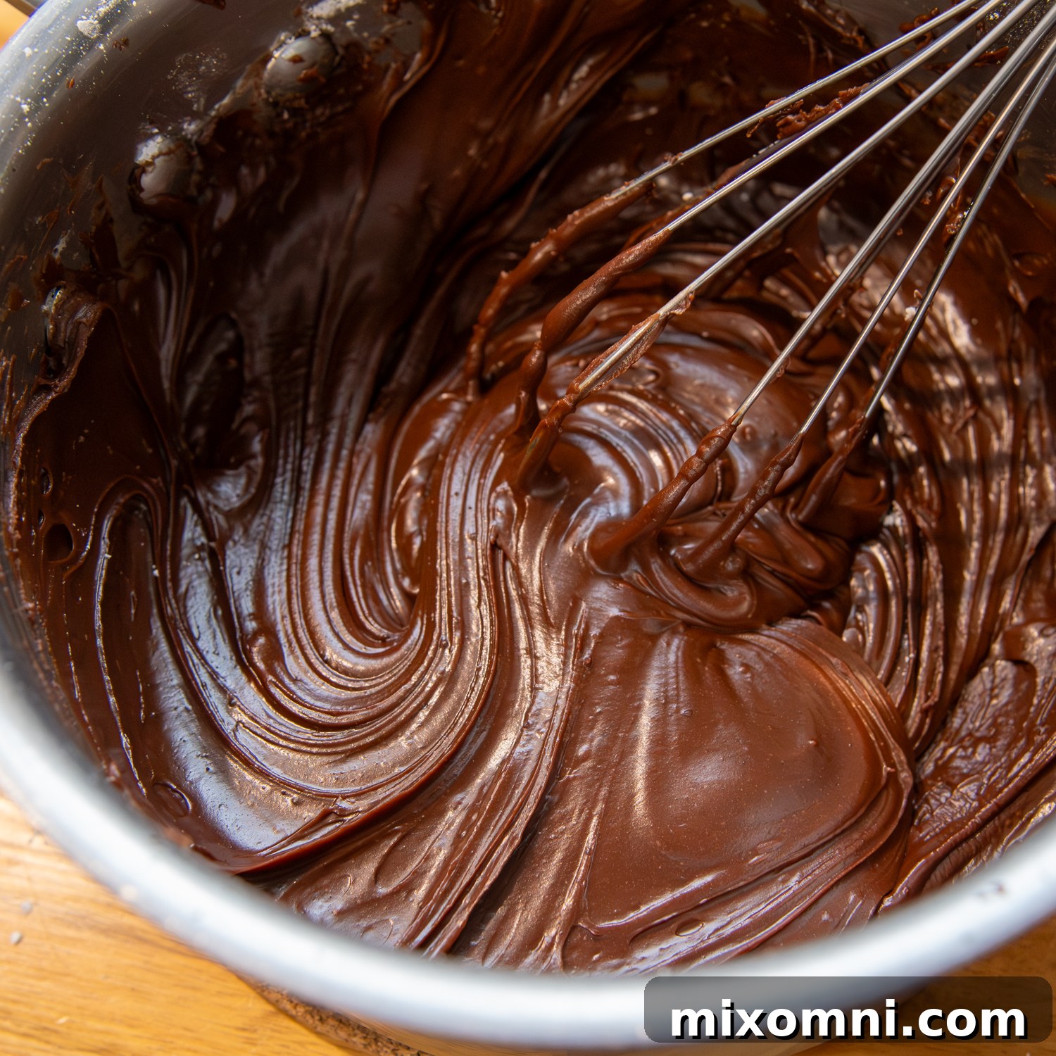 Whisking ingredients to smooth fully, preparing the chocolate glaze.