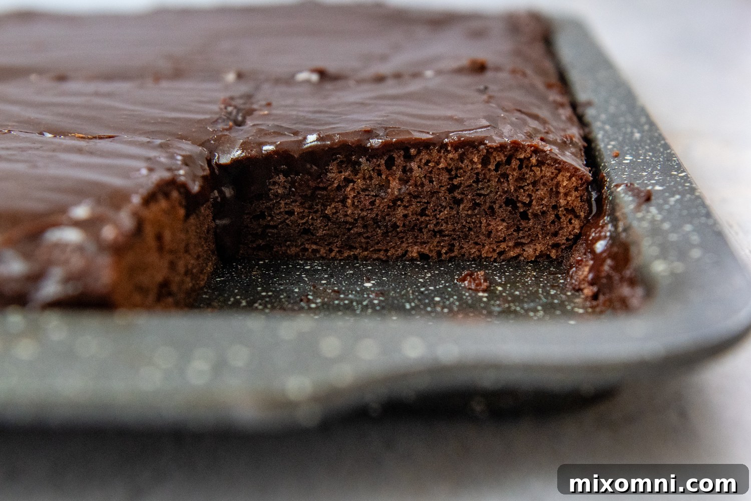 A glorious Gluten-Free Texas Sheet Cake in a pan with a slice having been removed, showcasing its rich, moist interior.