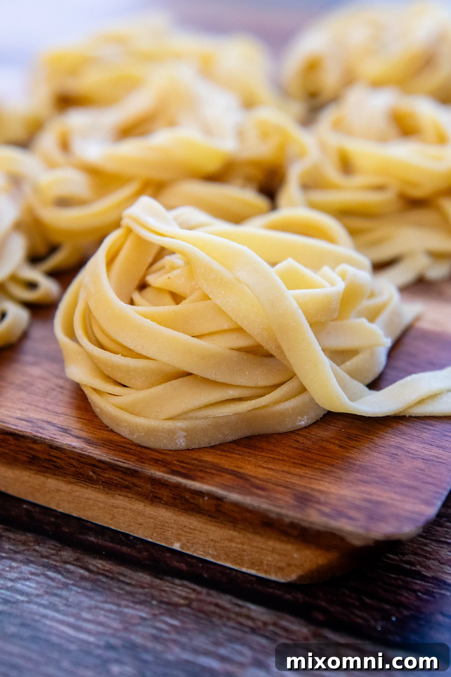 Beautifully folded fresh gluten-free pasta noodles resting on a wooden cutting board, ready for cooking.
