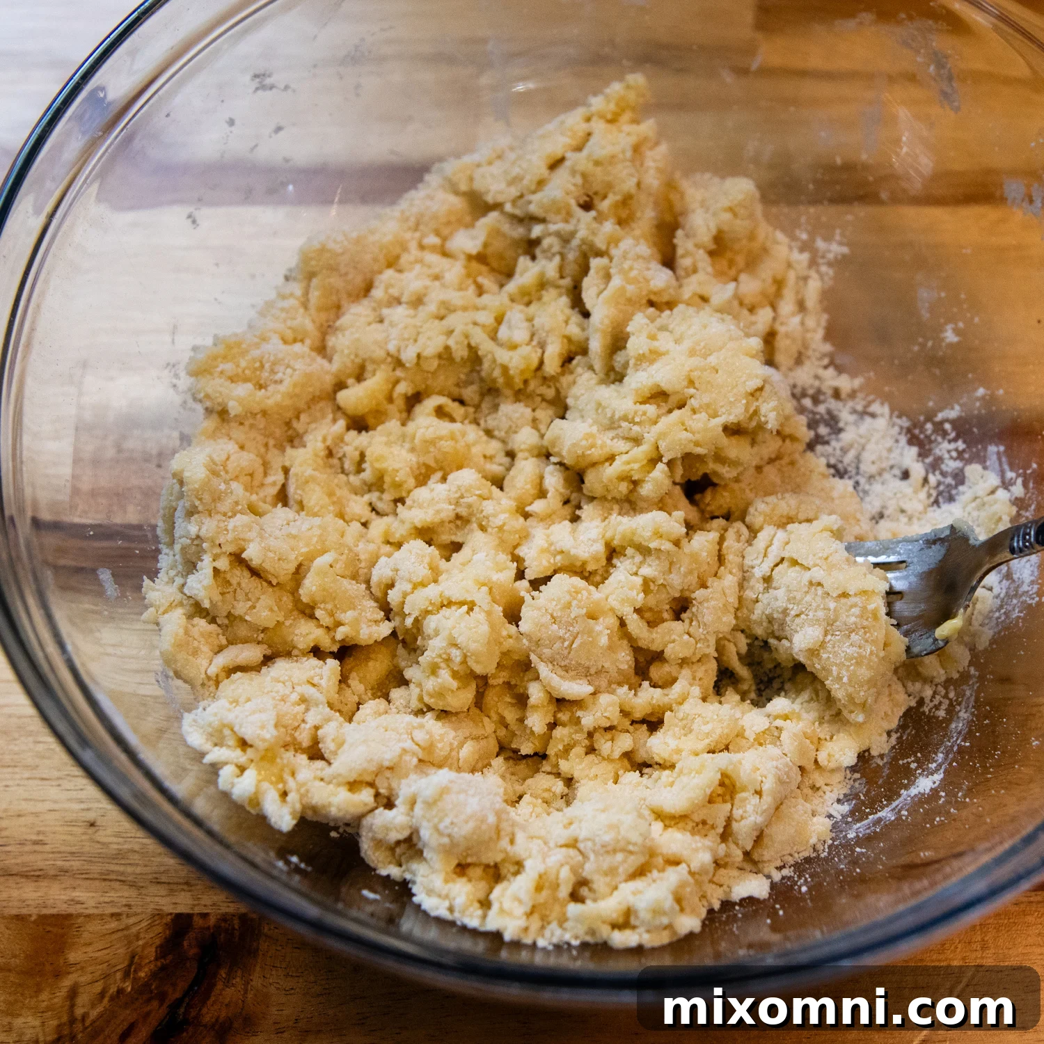 Gluten-free pasta dough being mixed by hand with a fork, showing the flour being worked in.