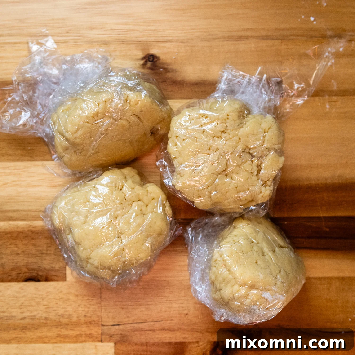 Four portions of gluten-free pasta dough, each individually wrapped in plastic to prevent drying.